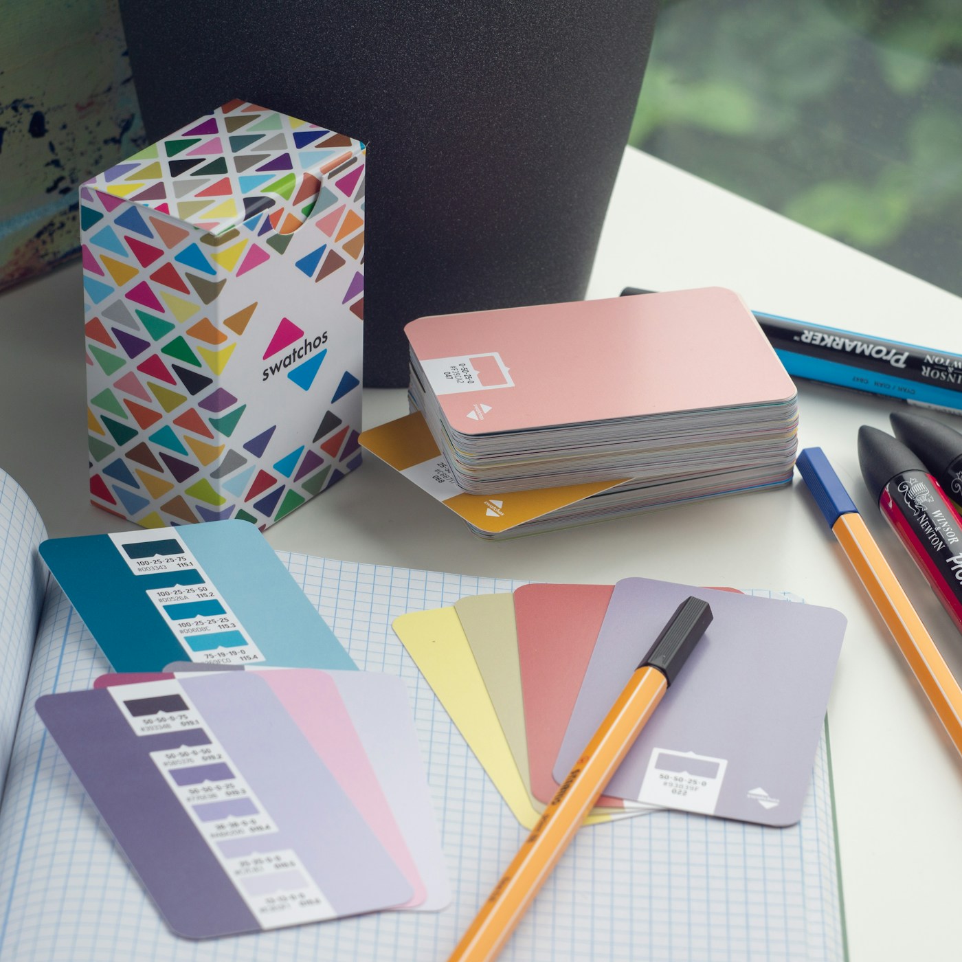 Farbkarten, Stifte und ein Notizbuch auf einem Designtisch